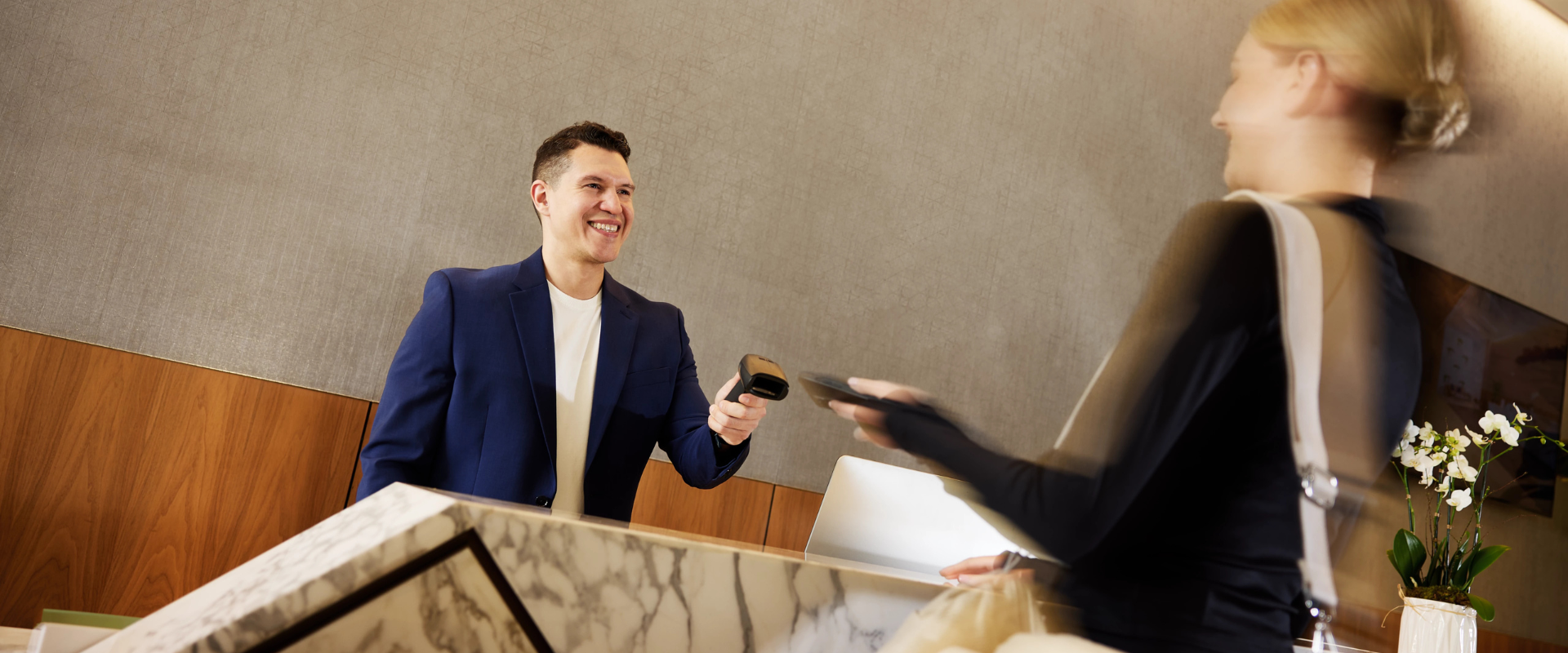 Young male concierge team member checking in a guest at the front desk at Life Time.