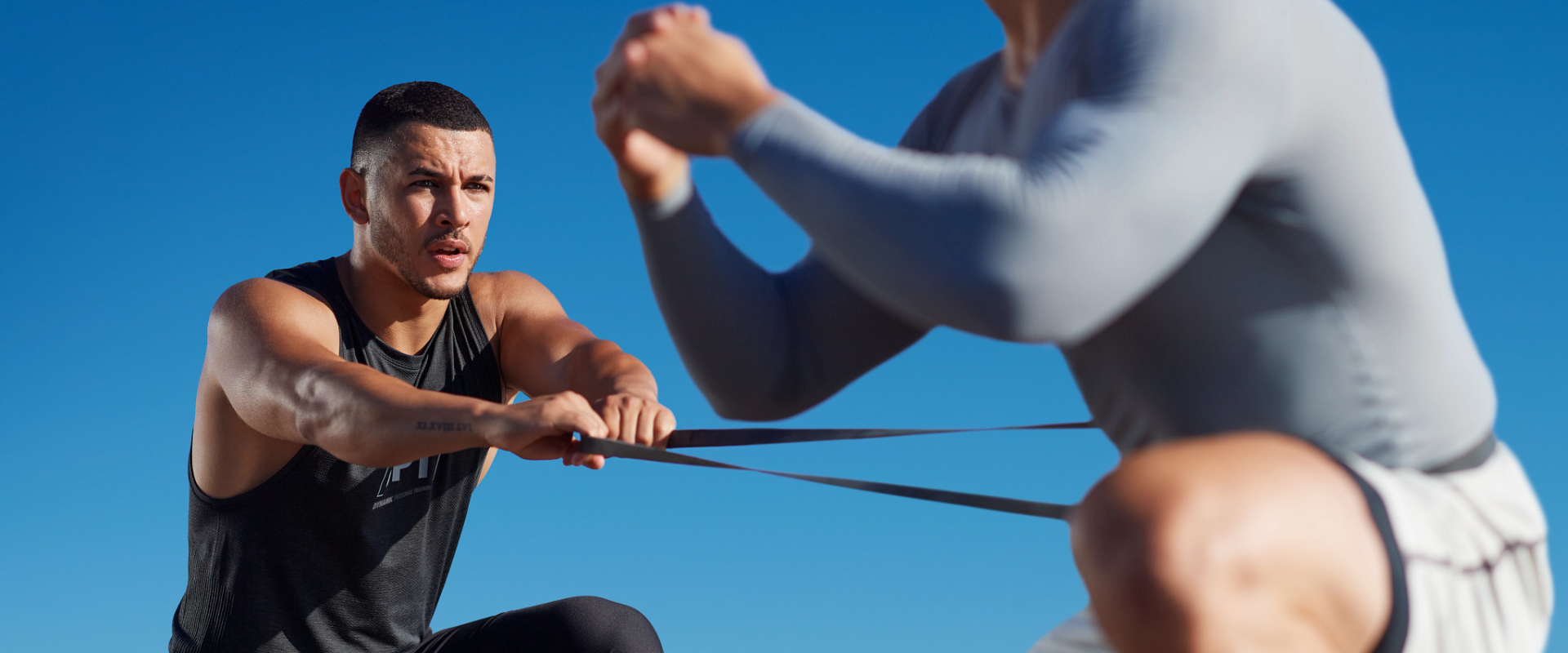 Life Time dynamic personal trainer assisting his client with an exercise band.