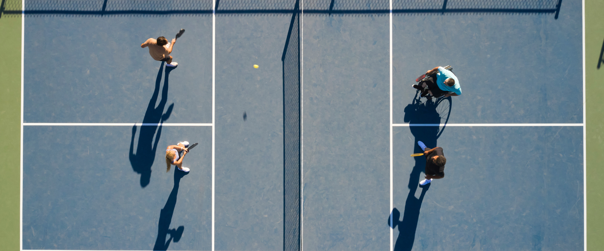 Four people playing a game of Pickleball on the Life Time Pickleball courts outside.