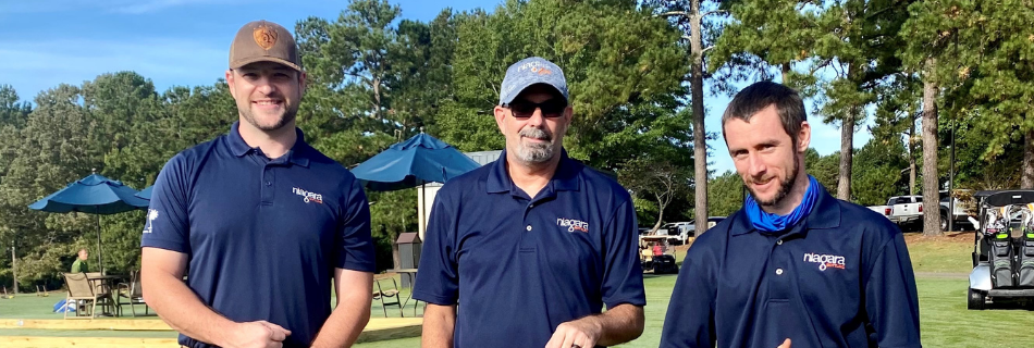 Niagara team members smiling on a golf course at an event supporting children's medical expenses