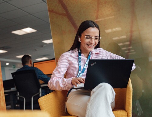 Young Philips employee sitting in the office and working on her computer.