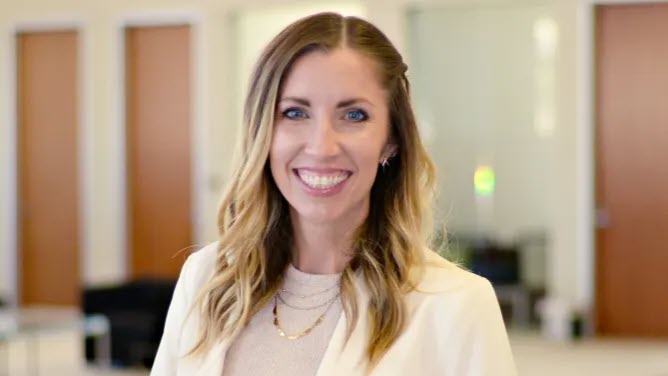 a picture of a woman standing in an office smiling at the camera.