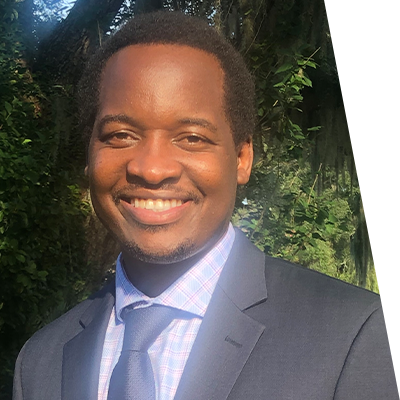 Portrait of man in professional clothes outside in front of trees smiling at the camera