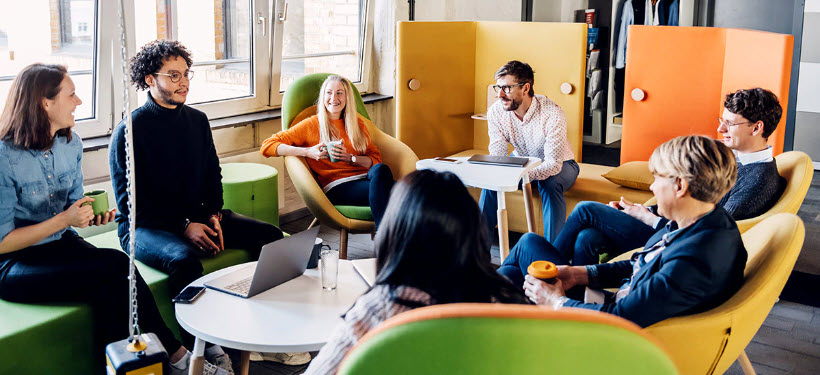 a photo of a group of people sitting in a circle while talking and smiling 