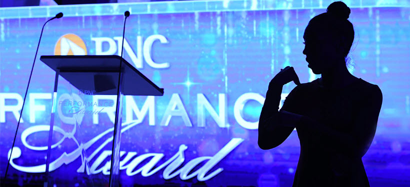 A silhouette of a woman standing in front of a blue PNC Performance Awards background 