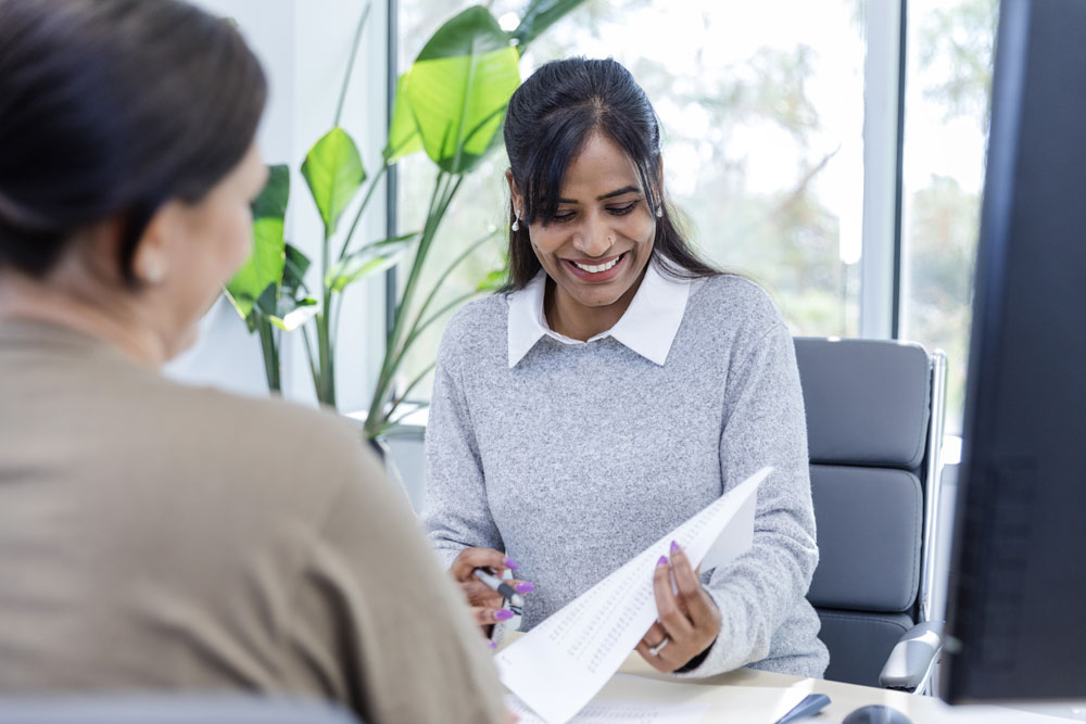 Woman sitting in an office chair looking at a piece of paper and smiling
