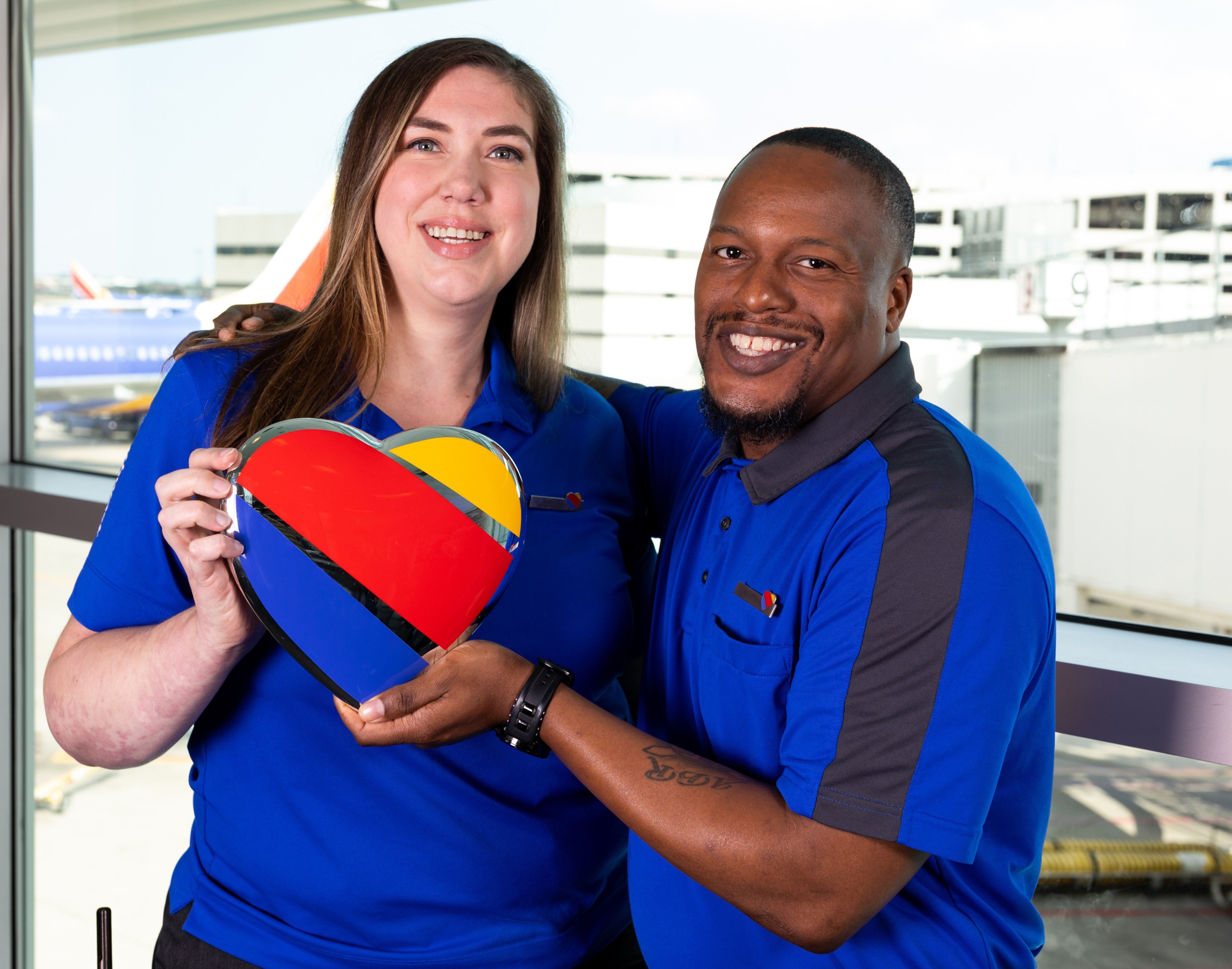 Two employees holding a Southwest Heart