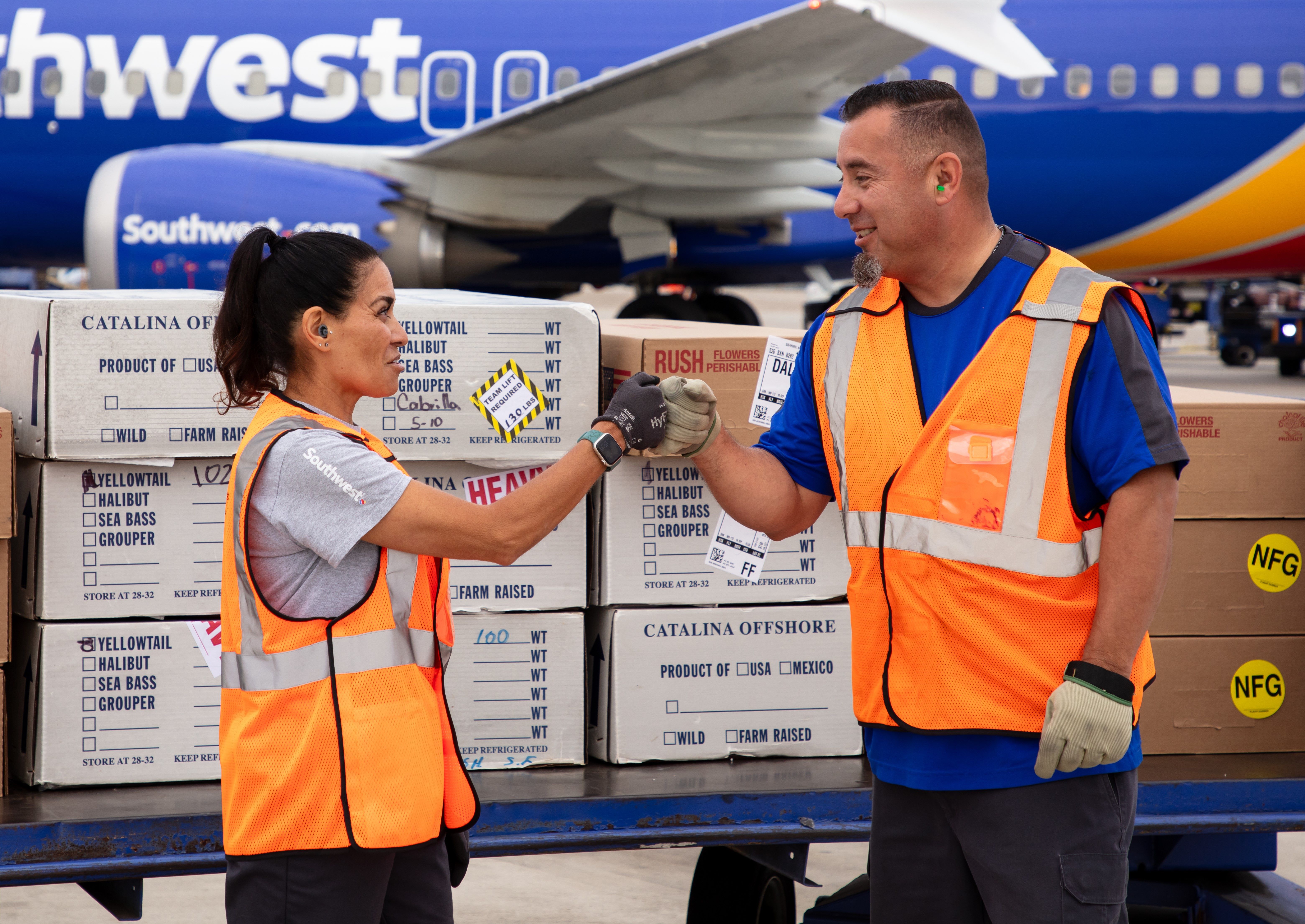 Cohearts fist bumping outside of an aircraft