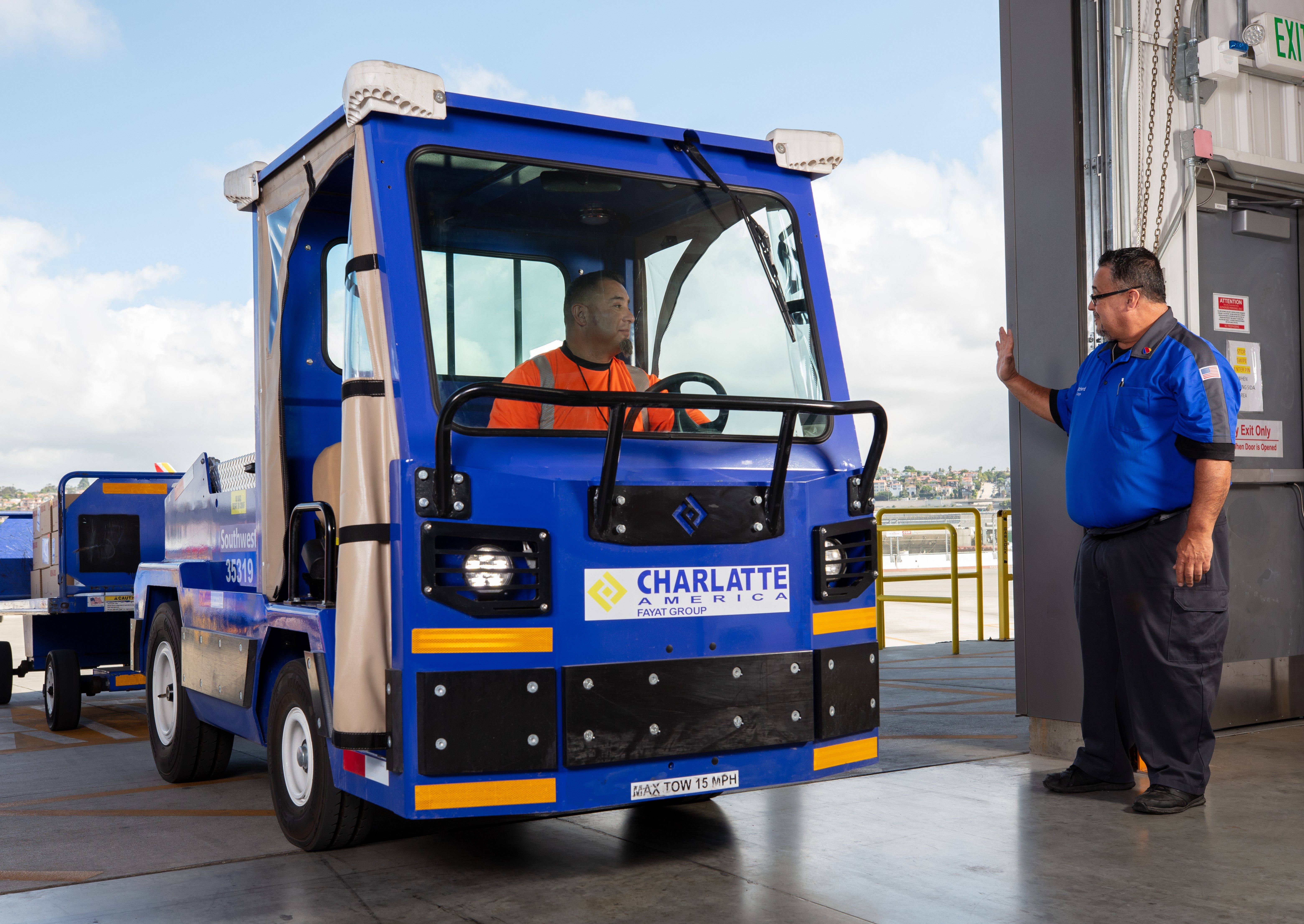 Cargo Agent driving a tug waving to another Cargo Agent.