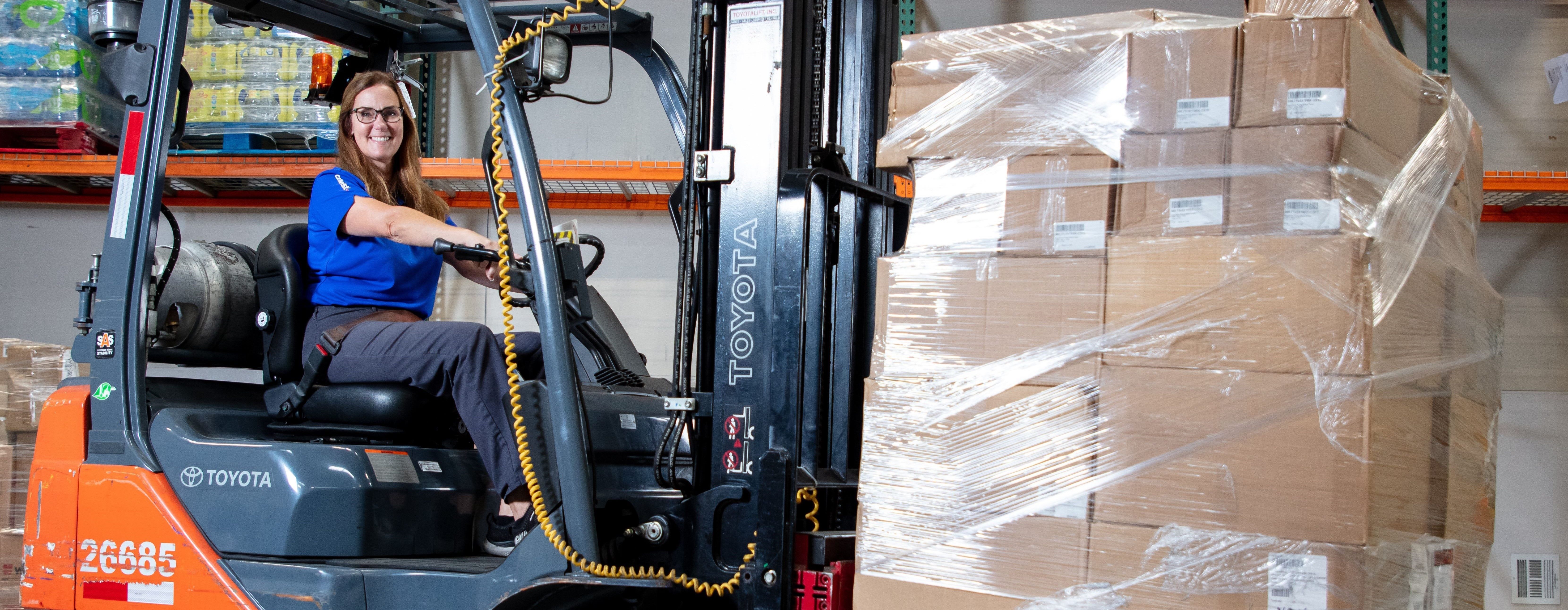 Cargo Agent smiling with cargo driving a forklift.