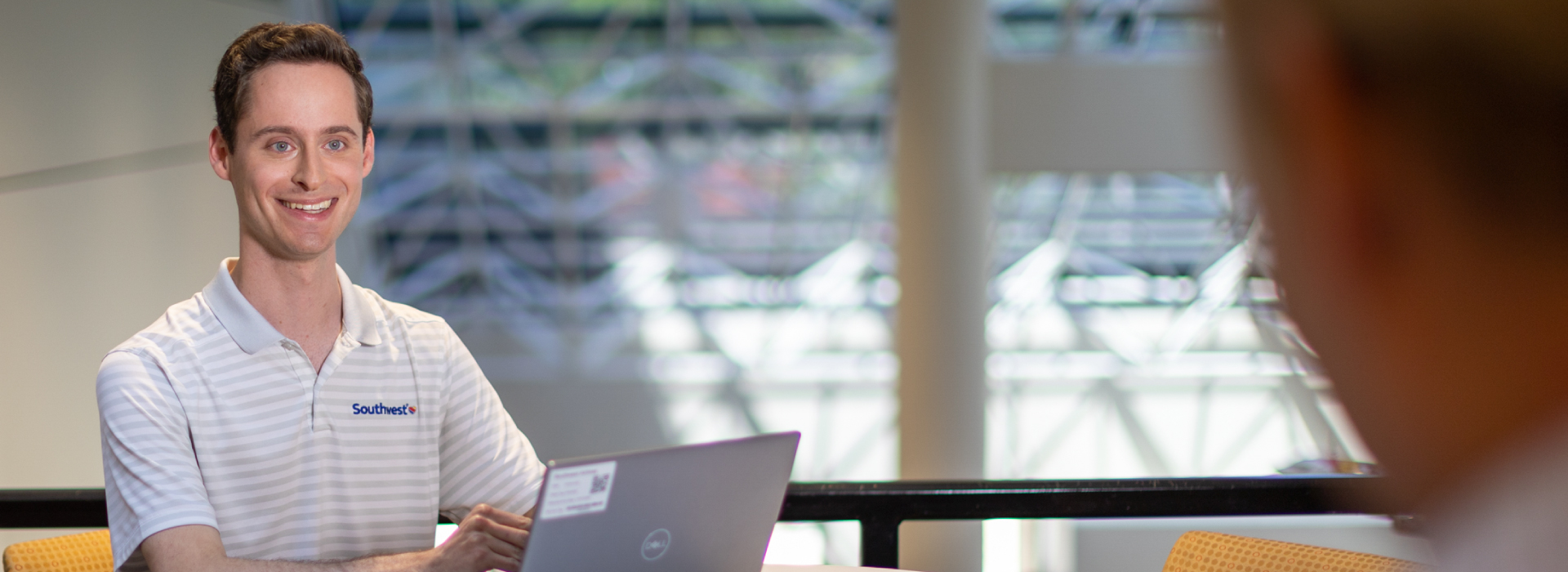 Photo of Technology Employee sitting at his laptop and smiling