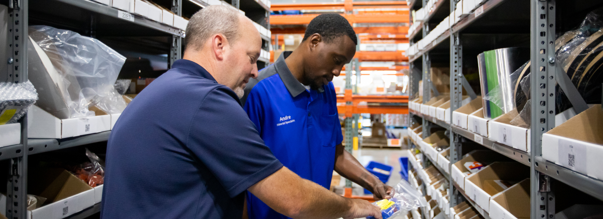Two coworkers talking with each other and looking at airplane parts
