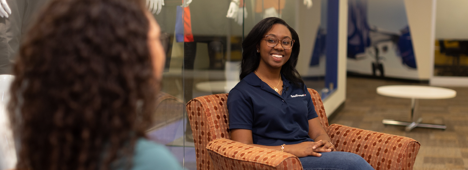A woman talking with her coworker while sitting in a chair