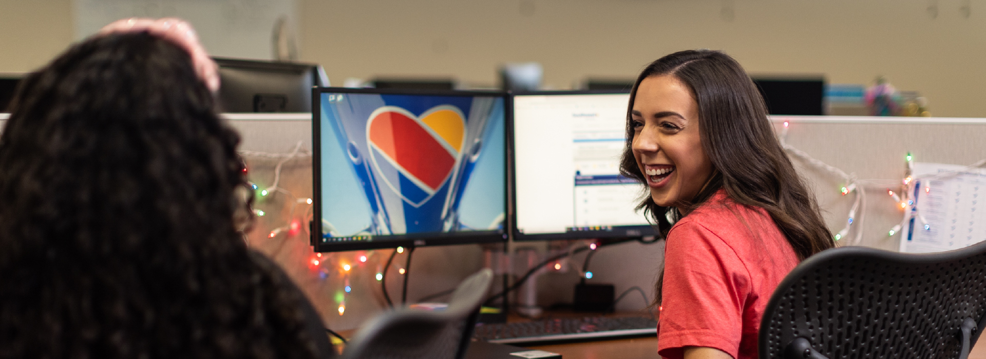 Two women working at their computers and laughing
