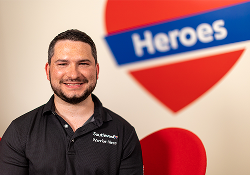 A Southwest Employee smiling in front of a "Heroes" sign