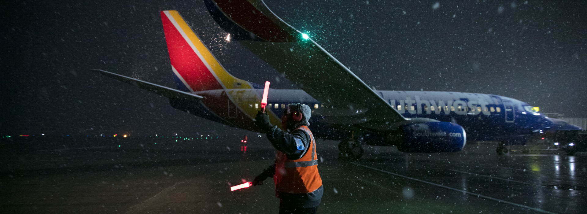Ramp Agent marshalling a plane in the snow