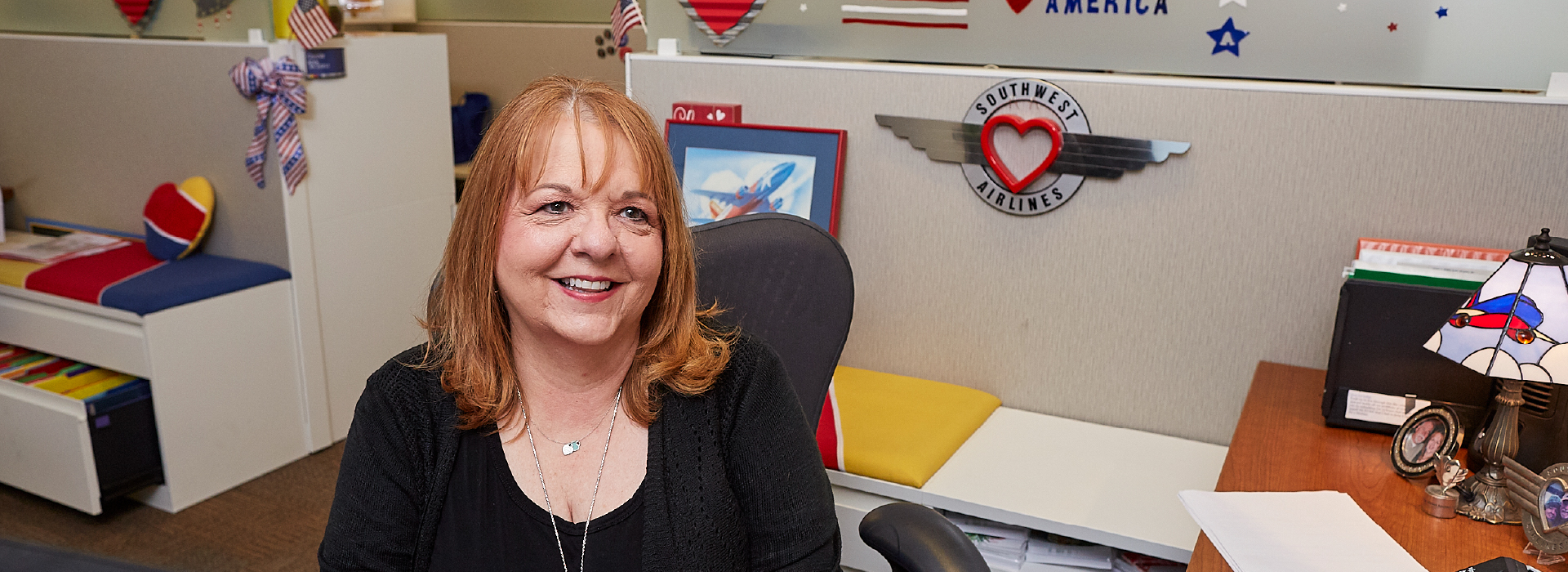 A woman sitting in her cubicle and smiling