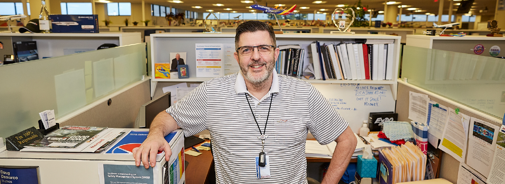 A man standing at his desk and smiling