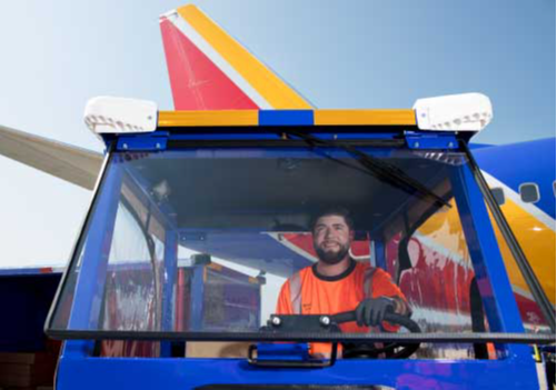 Image of female ramp agent stacking bags inside the belly of an airplane.