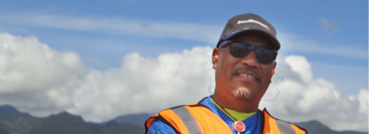 Image of Larry F., Southwest Ramp Agent smiling with mountains in the background.