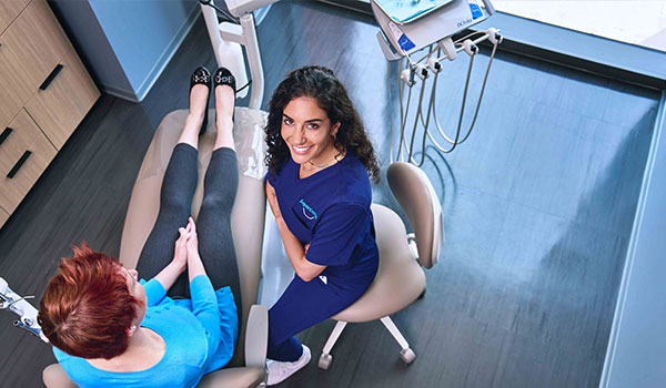 Dental hygenist talking with a patient in dental chair