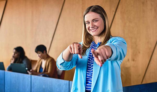 Front office worker smiling, pointing at the viewer