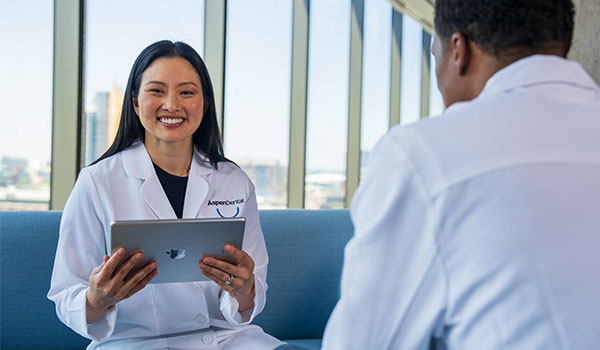 Two doctors speaking, one smiling, holding her iPad