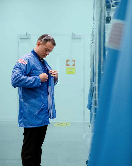 Ryan, a procurement manager, puts on a blue BAE Systems smock as part of his PPE before entering the manufacturing floor. 