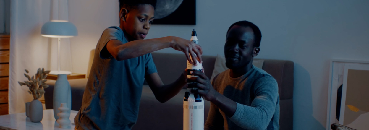 Father and son work on a model spacecraft in the living room.