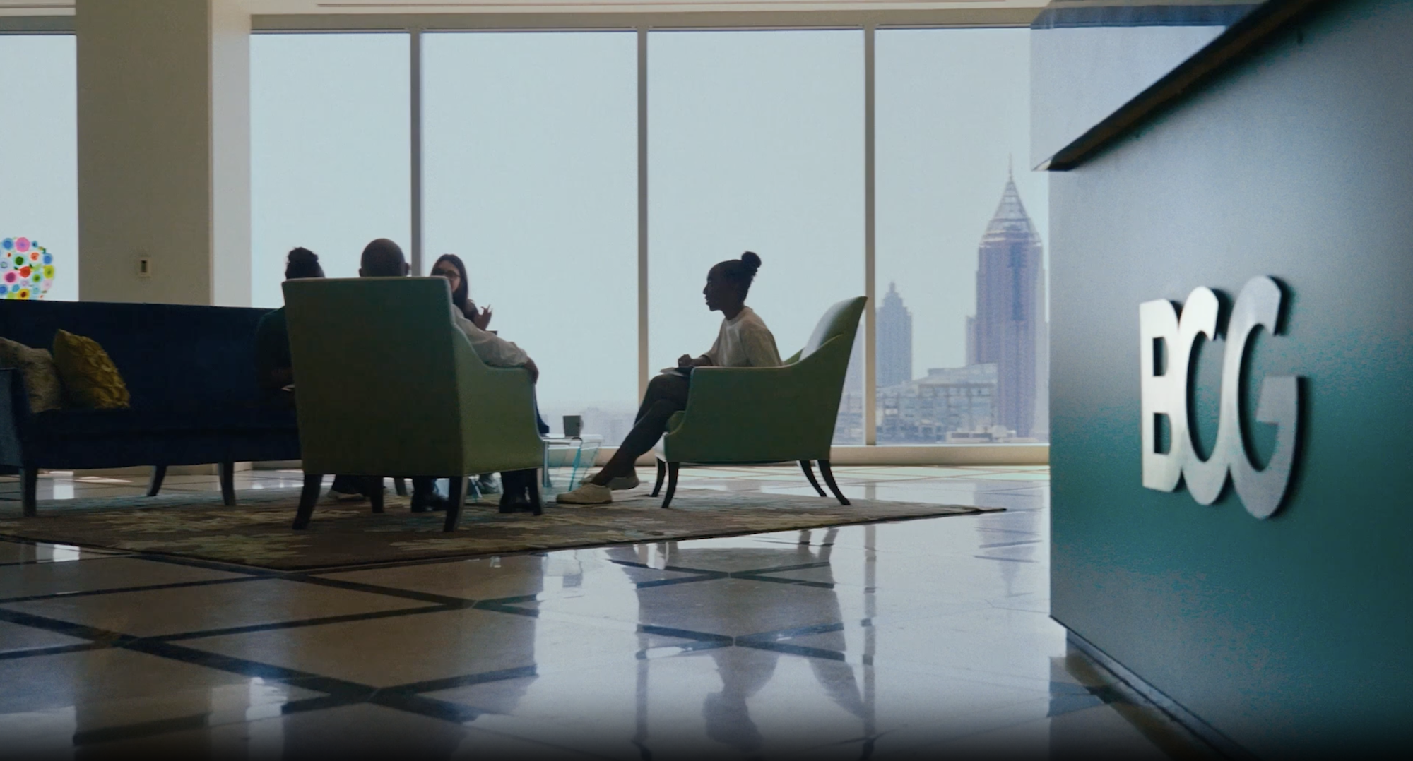 A modern BCG office lounge with a group of professionals engaged in conversation.