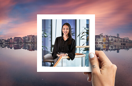 A hand holds a photo of four smiling people taking a selfie, with a vibrant city nightscape in the background.