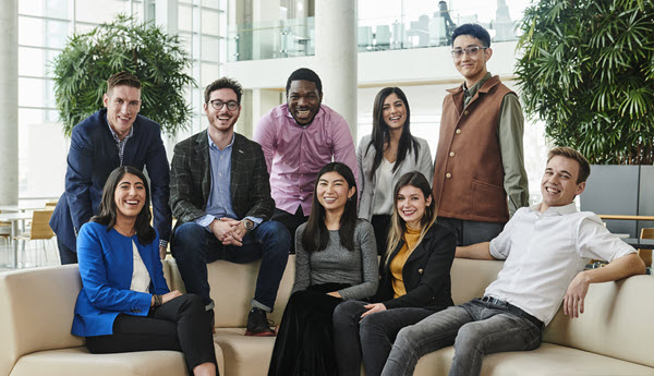 9 employés assis sur un canapé souriant à la caméra