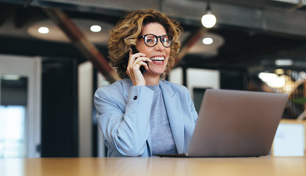Employé souriant au téléphone, assise avec un ordinateur portable