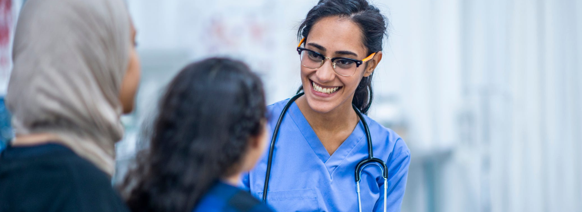 Clinical professional looking at mother and daughter in a hospital setting.