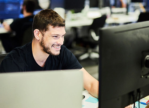 A smiling Chewy team member looking at a computer screen