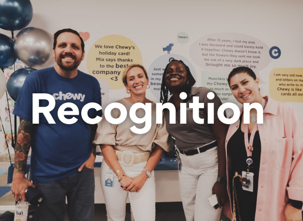 A Chewy FC team member wearing a yellow vest, pointing at his Chewy hat
