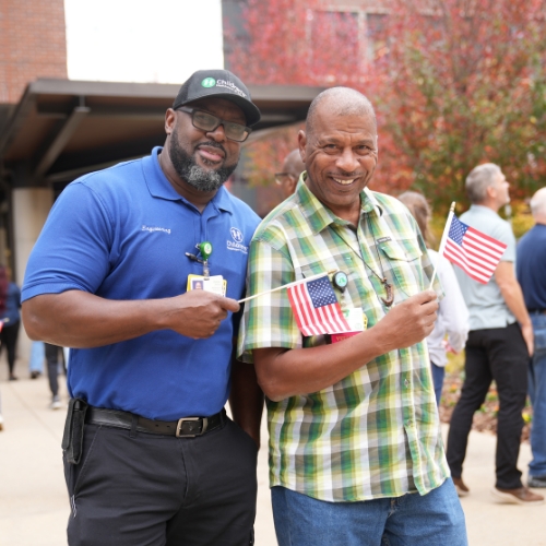 Two Children’s employees and veterans hold United States flags during Veterans breakfast event.