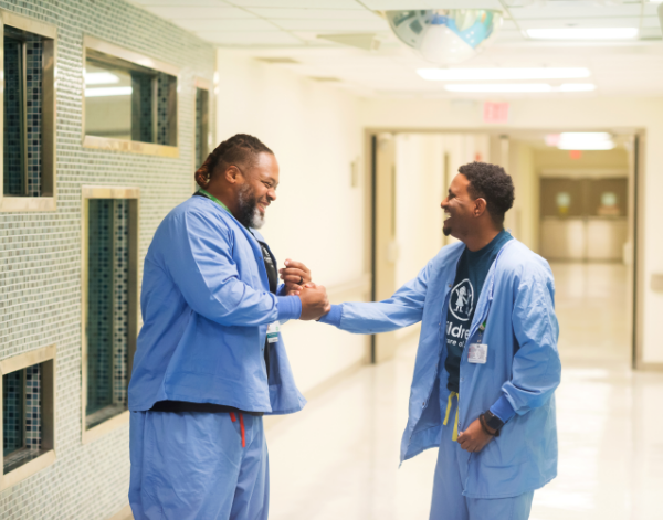 Children’s employees high-five in hospital hallway. 