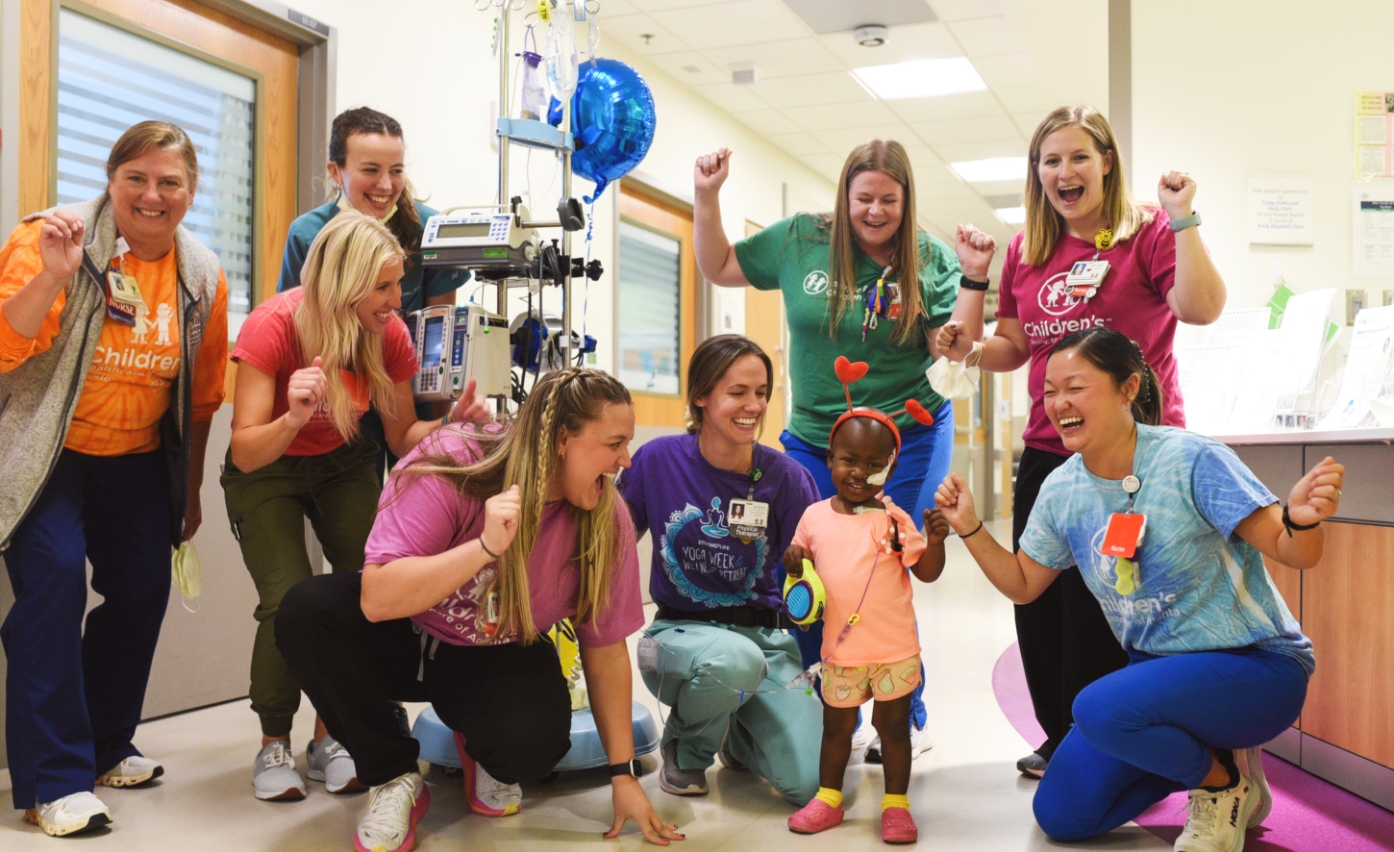 Children’s nurses cheering on young girl in hospital. 