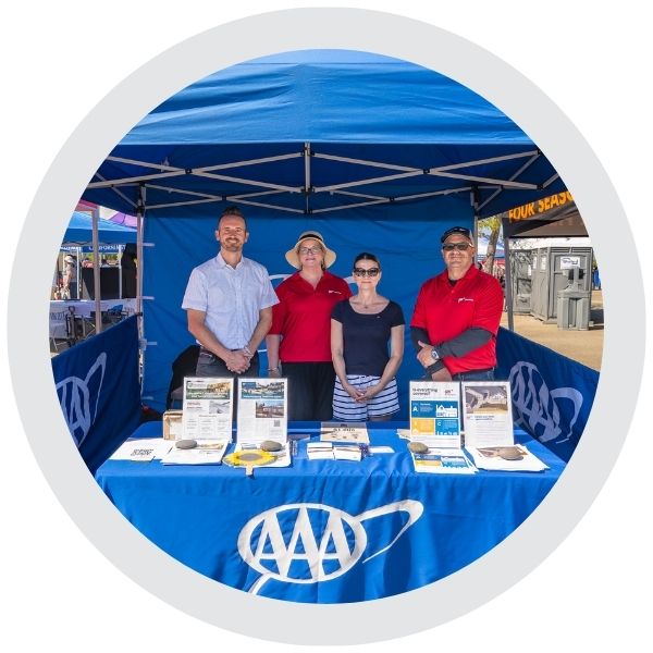 Employees standing behind an AAA‑branded table at a community outreach event 