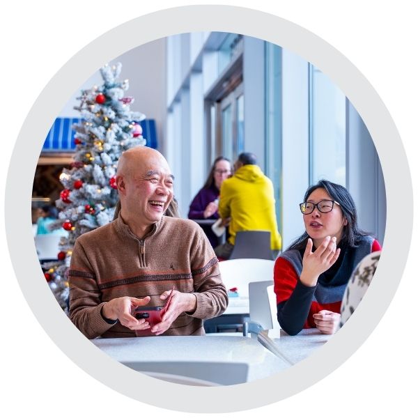 People seated at a table in a shared indoor space sharing laughter