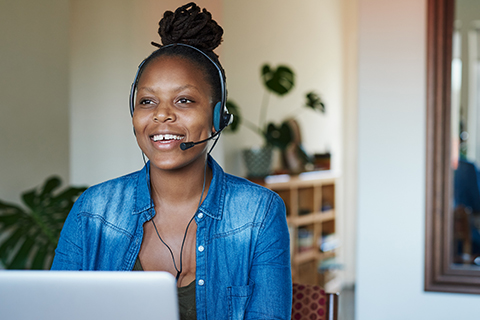 Smiling female wearing headset in front of laptop