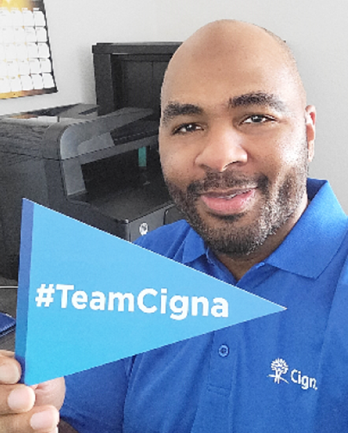 Photo of Cigna Group employee Bruce R. holding #TeamCigna pennant