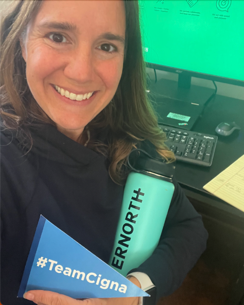 Photo of Evernorth employee Elizabeth C. holding a #TeamCigna pennant.