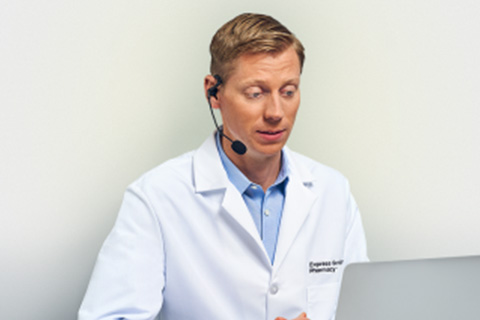 Pharmacist with headset sitting at laptop 