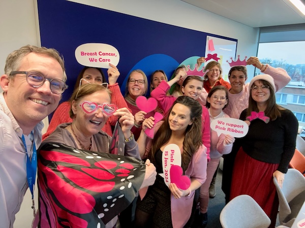 Belgium employees posing in a photo booth for breast cancer awareness