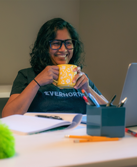 Employee working holding a mug wearing an Evernorth shirt