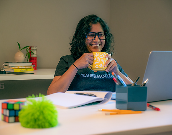 Employee holding a cup of coffee in front of her laptop