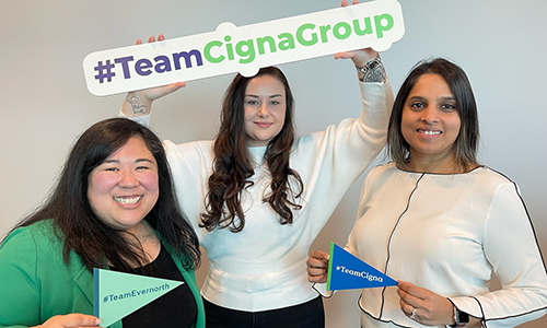 Three female employees posing with company signs