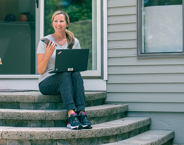 Employee working outside with her laptop while talking on the phone